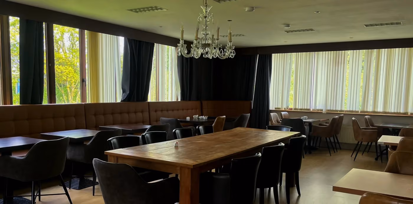 De zaal met kristallen luster, lange tafel en zicht op het groen