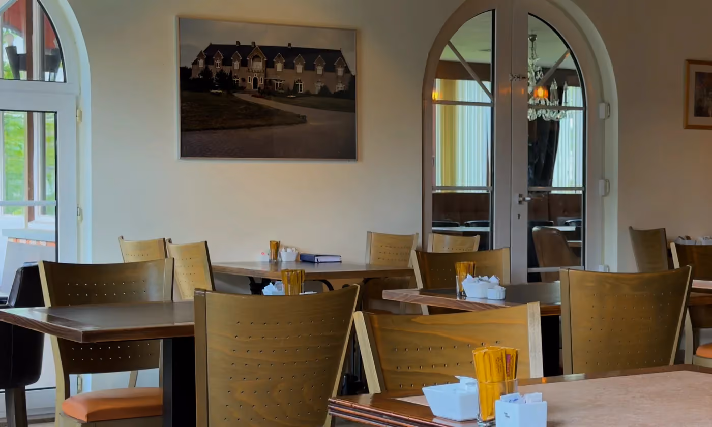 Zaal met gedekte tafels, klaar voor een gezelschap